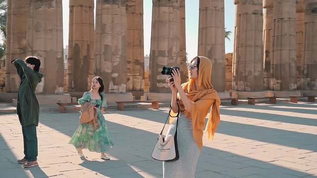 beautiful tourist wearing yellow scarf walking alone at sunny day enjoying luxor temple with ramsses ii statue in background, luxor, Egypt.