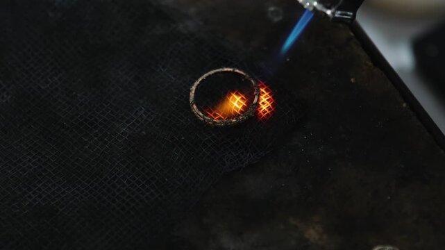 Ring maker using a blow torch to craft a ring. Manufacturing jewelry.