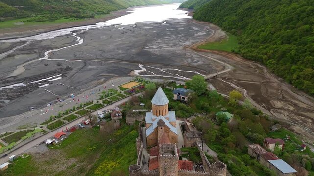 Aerial view of ancient stone walls and conical roofs of Ananuri Fortress, Georgia. Detailed view of medieval Georgian architecture and historical masonry against a dramatic sky.