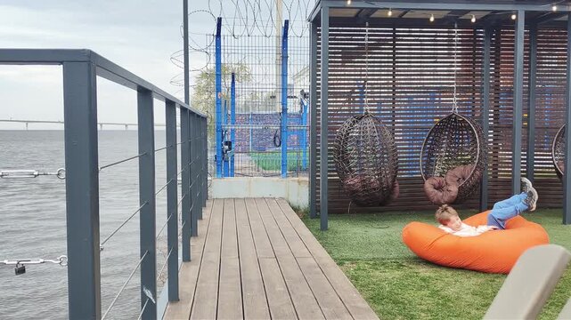 Dynamic action shot of a boy running and doing a mid-air somersault before landing on a large orange bean bag chair. Outdoor play, childhood fun, active lifestyle.