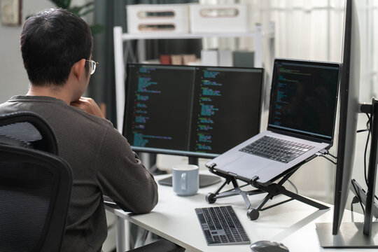 Programmer Working on Dual Monitors with Coding Software in Modern Office