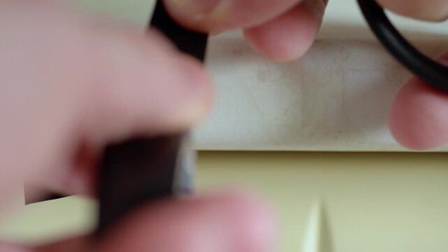 Hands applying tape strips on pipe surface to create black bands, scissors trimming ends, closeup maintenance scene with repetitive pattern and utility context