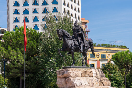 Tirana, Albania &mdash; August 20, 2025: Skanderbeg Monument on the main square with Et'hem Bey Mosque and modern skyscrapers under construction in the background on a sunny day.