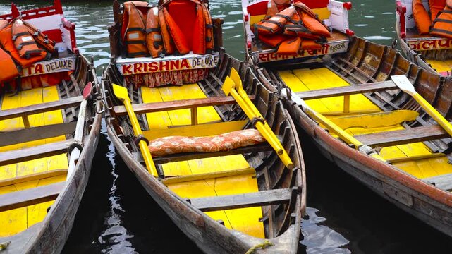 Close-up of vibrant wooden rowing boats with life jackets docked at a lake in India