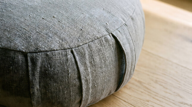 close-up gray meditation zafu cushion on wooden floor minimalist wellness setup