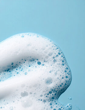 White soap foam texture on smooth blue background, soft natural lighting, delicate shampoo bubbles, clean hygiene and bath care