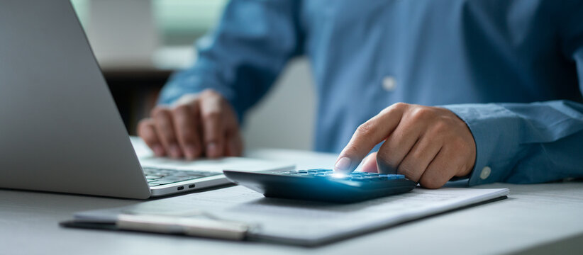 The concept of tax planning and tax calculation involves business people using laptops and calculators to fill out online income tax forms and make payments.