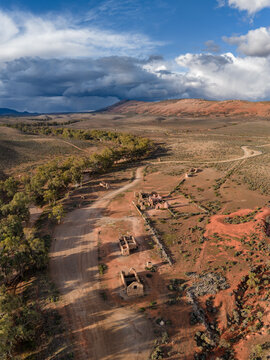 Aerial view of the historic stone ruins of Kanyaka Station along a winding dirt road in the dry outback landscape Flinders Ranges, South Australia, Australia.