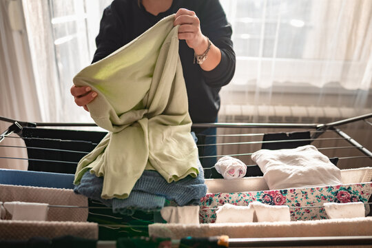 Woman drying laundry on a rack at home.