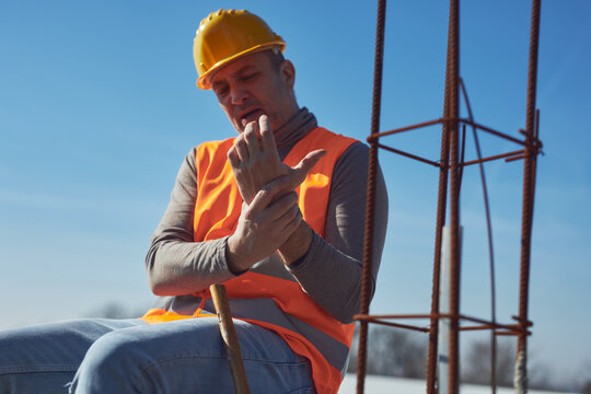 Construction worker having a accident and injured wrist on a construction site outdoors.