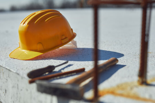Construction tools and helmet on a cement foundation with iron rebar.