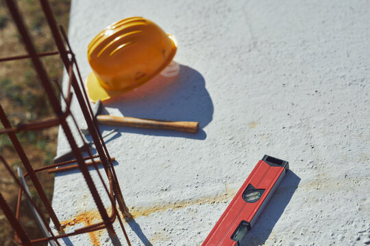 Construction tools and helmet on a cement foundation with iron rebar.