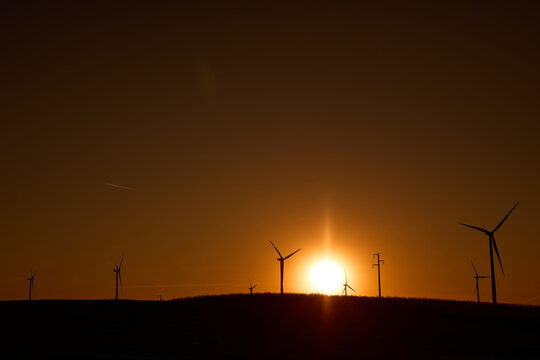 Wind turbines at sunset in green field &ndash; renewable energy, clean power, sustainable future.