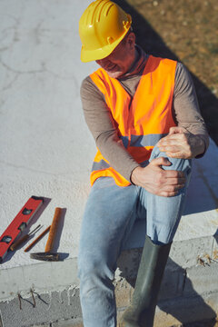 Construction worker having a accident and injured knee and leg on a construction site outdoors.