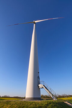 Wind turbines at sunset in green field &ndash; renewable energy, clean power, sustainable future.