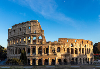 Obraz premium Famous Coliseum in Rome. Colosseum, or Coliseum. Sunset at huge Roman amphitheatre, Rome, Italy, Europe. Famous touristic place in the world and Europe. Beautiful blue sky background.