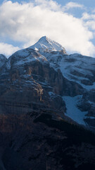 Fototapeta premium Snow capped mountain peak with clouds in blue sky