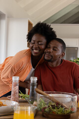 African American couple leaning together at dining table, sharing salad and orange juice © wavebreak3