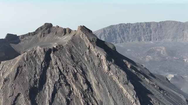 Close-up aerial of the sharp, rugged crater rim of Pico do Fogo. Detailed view of ancient basaltic rock formations and steep geological ridges in Cabo Verde