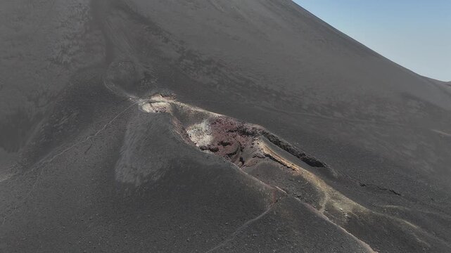 Dramatic drone perspective of a volcanic crater vent on the flank of Fogo Volcano, Cabo Verde, revealing unique textures of solidified lava and basaltic soil