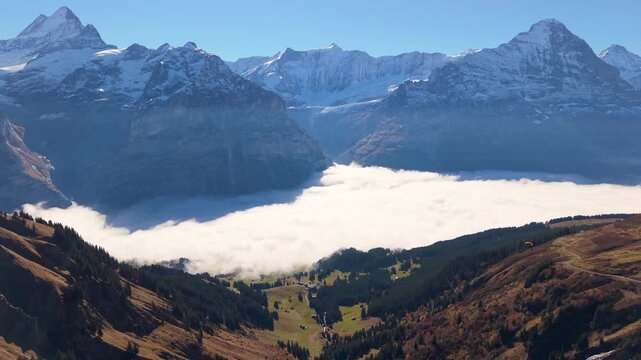 Wide aerial view of Grindelwald valley and alpine village with morning sea of clouds surrounded by the Eiger and Wetterhorn mountains. Canton of Bern, Switzerland.