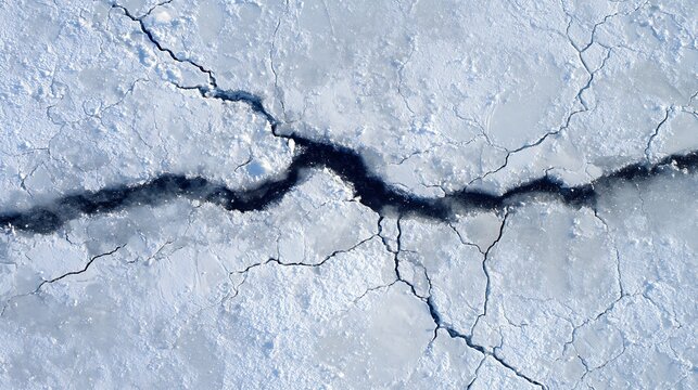 Cracked ice surface with deep fracture showing dark arctic water underneath during winter season in cold polar region with intricate natural patterns and frozen crystalline textures