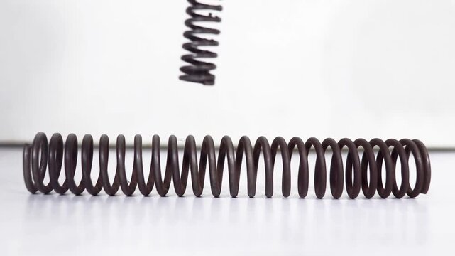 Metal coil spring expanding and contracting in a rhythmic motion for industrial engineering mechanical testing sequences