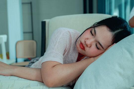 Woman is taking nap soundly during the day to relax at home daydreaming and resting on a comfortable sofa in the air conditioned guest room which helps her sleep better.