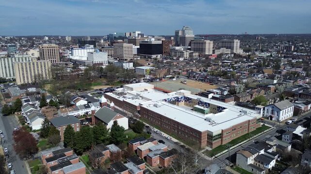 East side campus large institutional building anchors East Side grid near E 6th St, dense residential blocks extending toward downtown. Varied roofing, brick tones, tree shading in Wilmington, DE