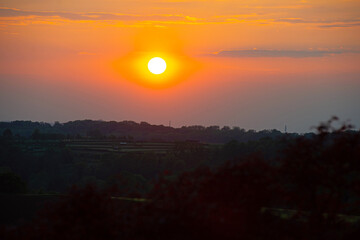 Obraz premium Sundown over fields and trees in a hilly landscape under a colorful evening sky in springtime, Voeren, Limburg, Belgium, May, 2026