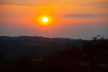 Obraz premium Sundown over fields and trees in a hilly landscape under a colorful evening sky in springtime, Voeren, Limburg, Belgium, May, 2026