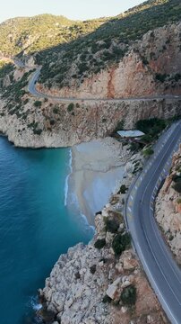 Discover the breathtaking views of Kas, Kaputas Beach, Turkey, where turquoise waters meet rugged cliffs. A serene road winds along the coast, inviting travelers to experience this paradise.