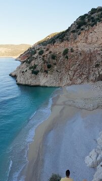 Breathtaking views of Kas, Turkey, reveal stunning cliffs and pristine beaches. Witness two friends enjoying the calm waters of Kaputas Beach, creating a perfect backdrop for relaxation and adventure.
