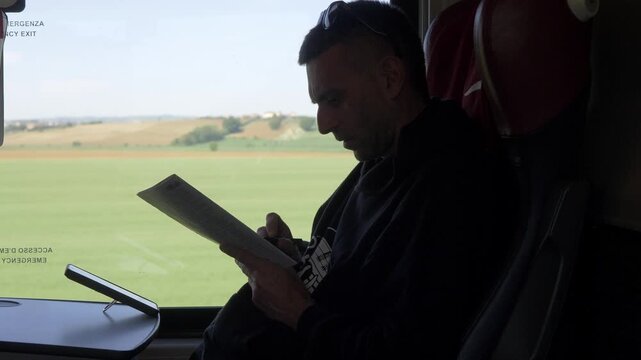 Vertical: Young dark-haired man solving a crossword puzzle on a train seat, enjoying a relaxing and mentally engaging moment during travel.