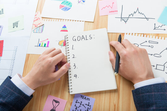 A person writes down his goals in a blank book.
