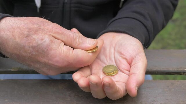 Mature man hands moving a few coins between fingers while counting limited savings and managing scarce money.