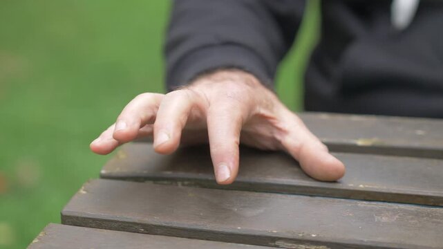 Mature man hands tapping on a table, expressing nervous anticipation, impatience, and emotional tension while waiting.