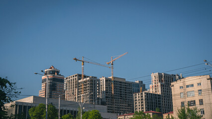 Construction site with tall yellow tower cranes and unfinished high-rise concrete buildings against a clear blue sky in Kyiv, Ukraine. Urban development and architecture industry concept. © Вита Курило