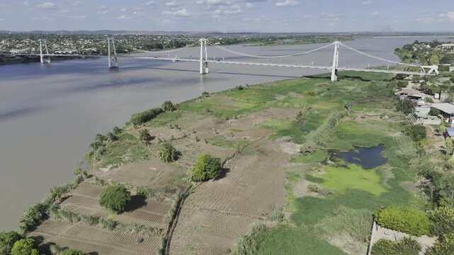 Drone lowers over swampy area on border of Zambezi River with view of Samora Machel Bridge on a sunny day in Tete, Mozambique
