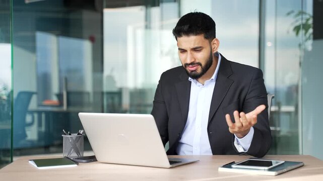 Disappointed businessman having difficulty making transaction using laptop while sitting at desk at workplace in business office. Frustrated confused worker having problems working online on computer