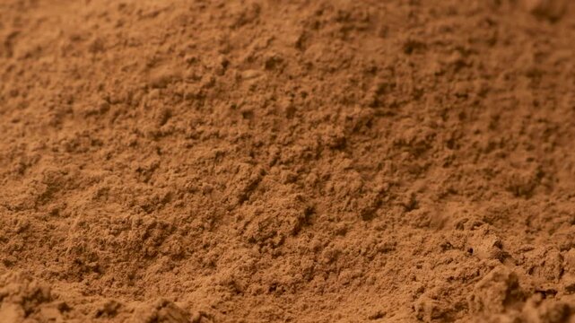 Close up of aromatic cacao powder pouring onto a pile in slow motion.