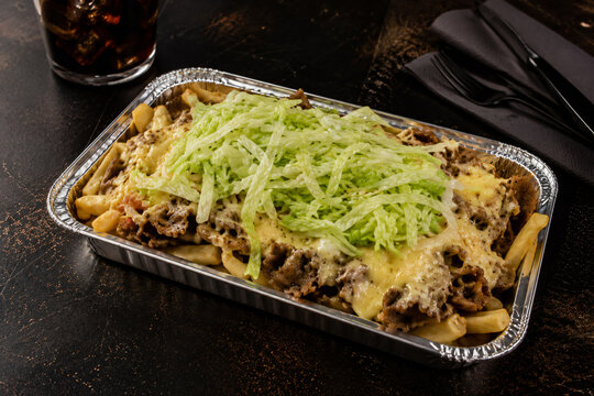 Cinematic Dutch kapsalon kebab fries in aluminum tray on dark studio table