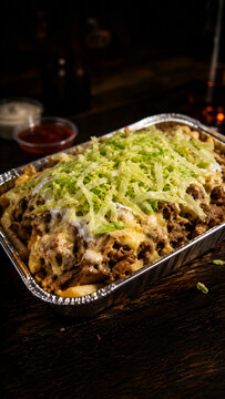 Loaded Dutch kapsalon with garlic sauce and chili sauce on dark table
