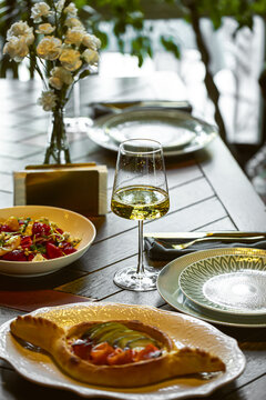 Fine dining table setup with white wine and gourmet dishes in cozy restaurant atmosphere with flowers