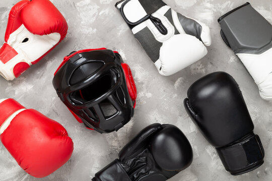 Boxing helmet and gloves on concrete background, top view.