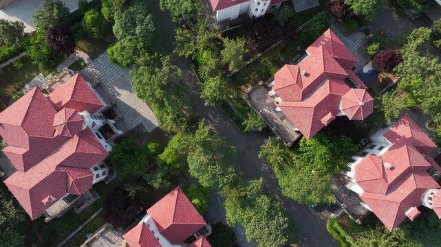 Aerial view of red-tiled villas surrounded by lush green trees and well-landscaped gardens