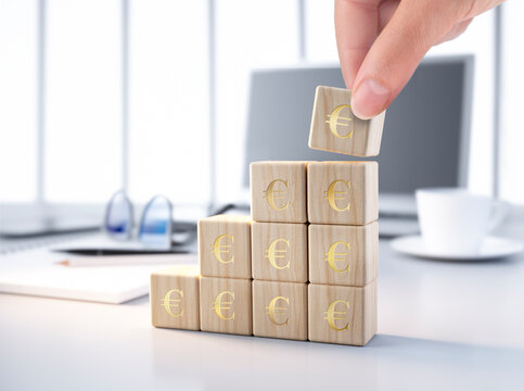 Hand placing dice with Euro symbols on desk on other stacked dices - 3d illustration at desktop scene with laptop and desk accessories