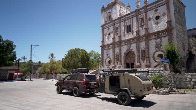 An SUV pulls a teardrop camper trailer as it drives through San Ignacio near the mission church in Baja California, Mexico.