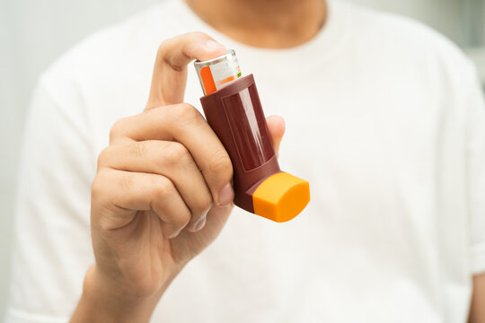 Asthma and chronic obstructive pulmonary disease COPD, Asian young man using metered dose inhaler MDI.
