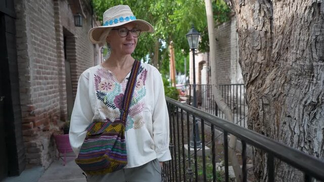 Mature woman walks through San Ignacio, exploring the mission town and observing the historic buildings and local plants in Baja Mexico.